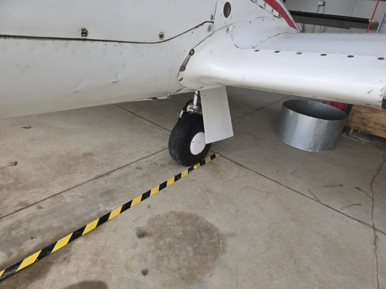 Airplane landing gear on concrete floor in hangar.