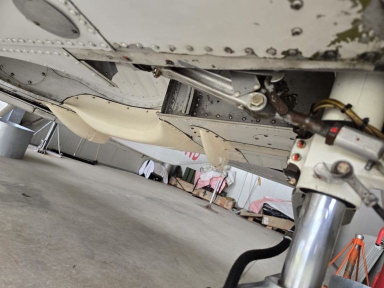 Underside view of aircraft landing gear in a hangar.