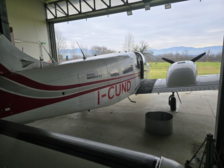 Piper Seneca II airplane in hangar with mountains view.