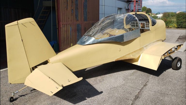 Unfinished light aircraft parked outside hanger