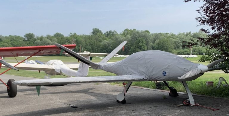 Covered airplane on airfield with green scenery