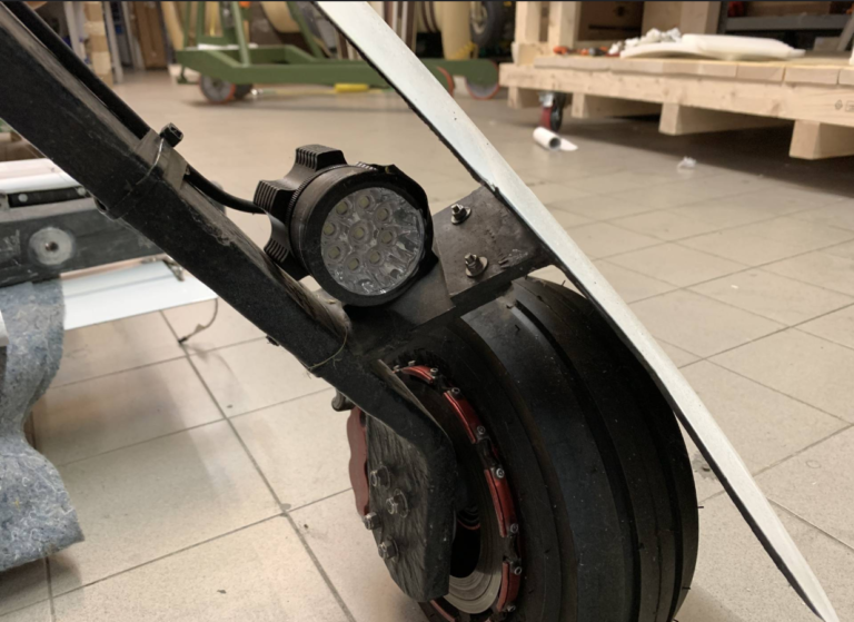 Close-up of electric scooter wheel and LED light.