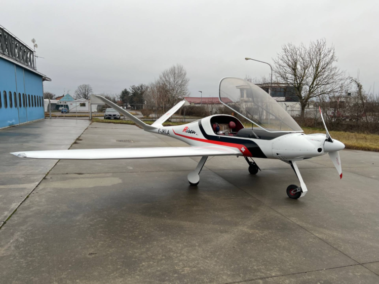 Small single-engine propeller aircraft parked on tarmac.