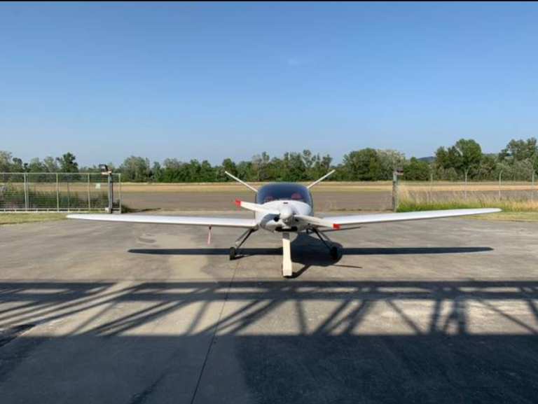 White airplane on airfield under blue sky.