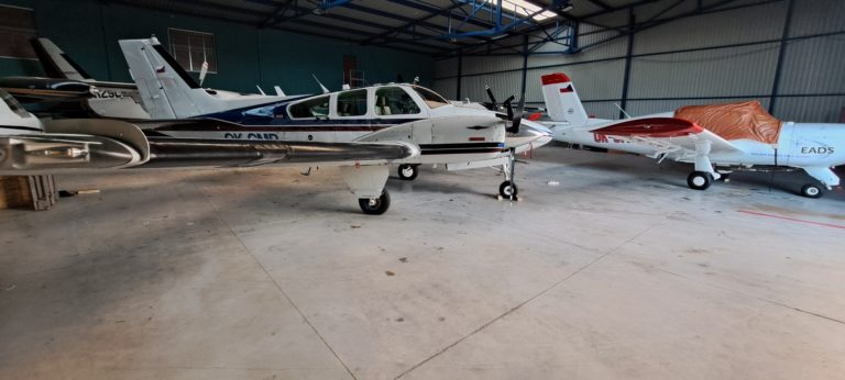 Airplane hangar with small aircrafts parked inside.