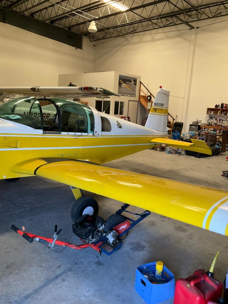 Yellow aircraft in hangar with maintenance equipment.