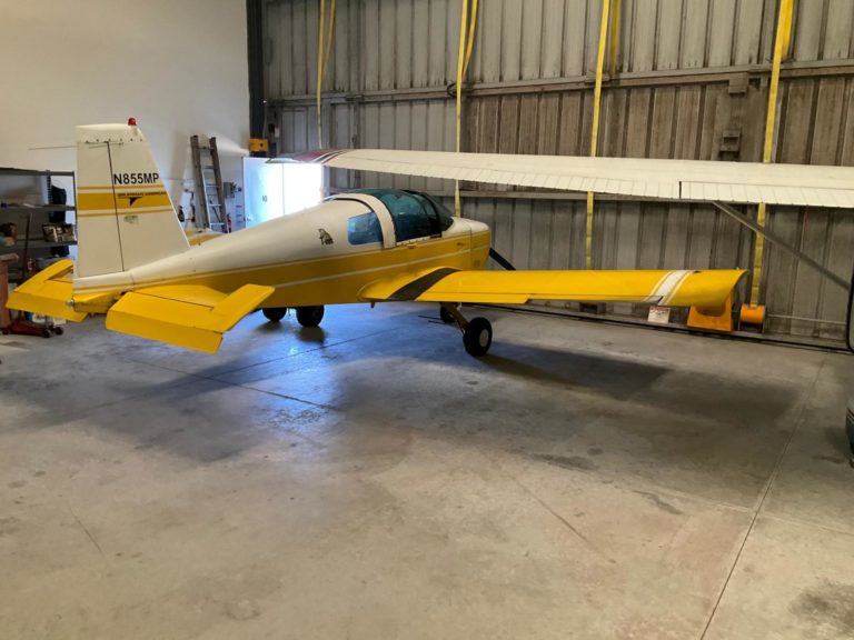 Yellow small aircraft parked in a hangar