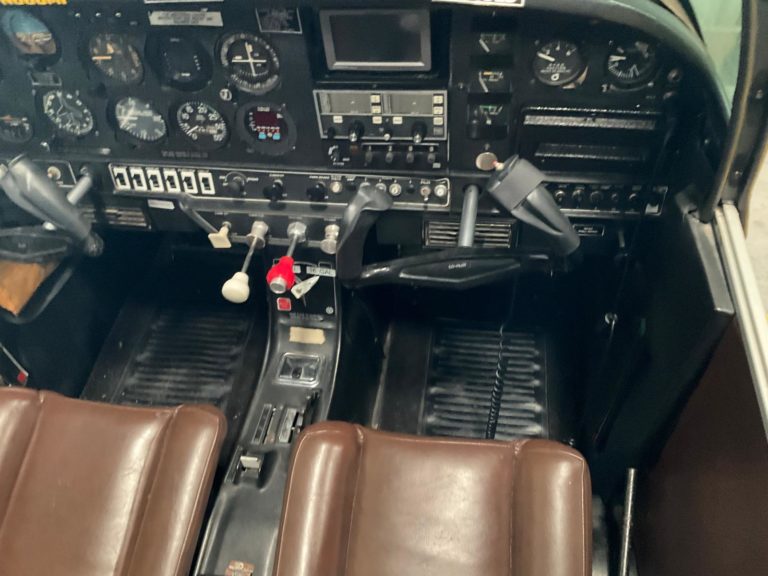 Small aircraft cockpit with instruments and controls.