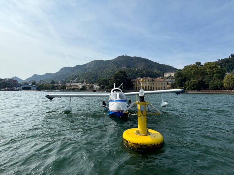 Seaplane docked on a lake with mountains view.