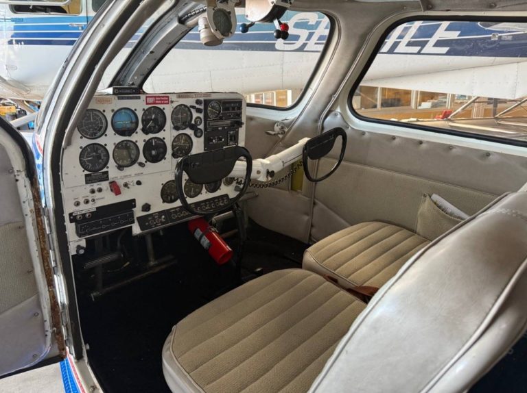 Small aircraft cockpit interior with controls and seats.
