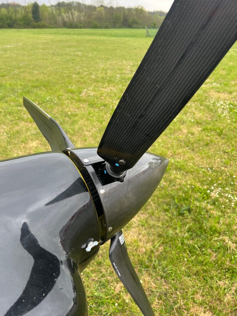 Black aircraft propeller on grassy field.