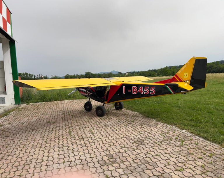 Yellow light aircraft parked on paved surface.