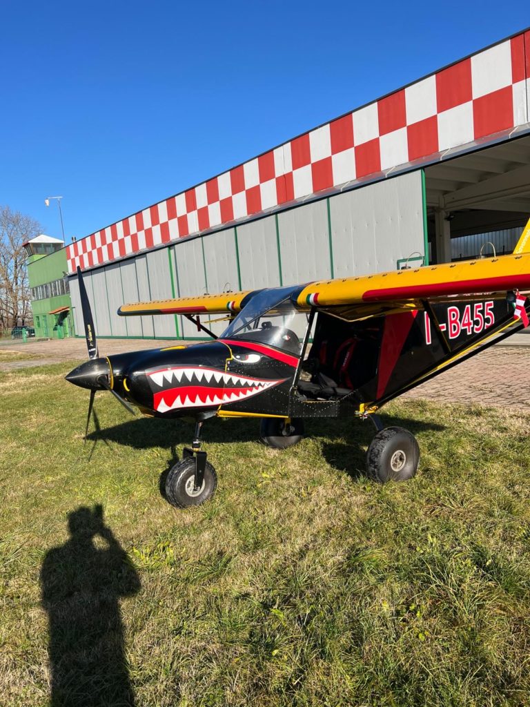 Small aircraft with shark mouth design by hangar