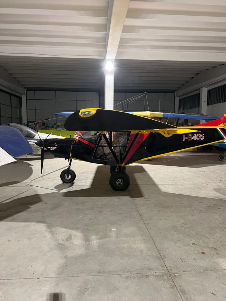 Small propeller airplane parked inside a hangar.