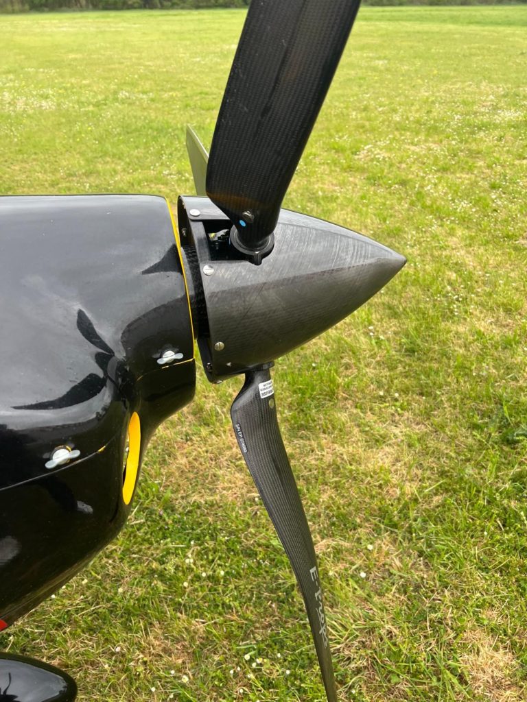 Close-up of black airplane propeller on grass field.