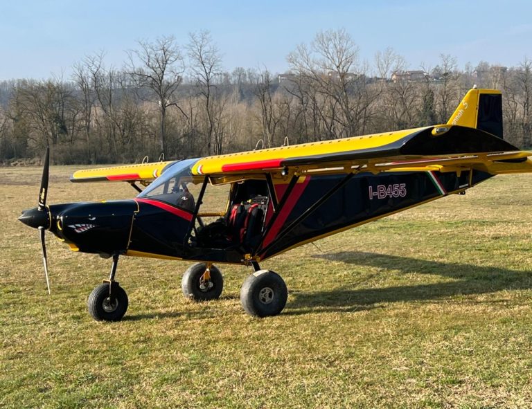 Yellow ultralight aircraft on grassy field.