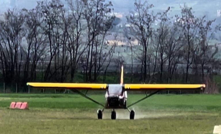 Small yellow plane on grassy field landing