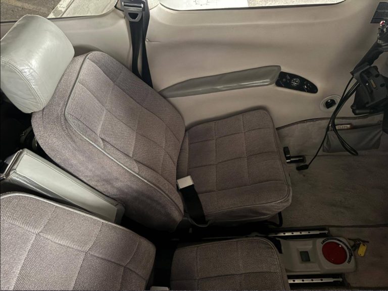 Gray car interior with two seats and seatbelts.