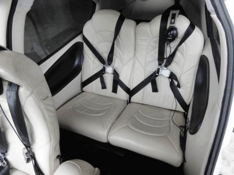 Two-seater airplane interior with seatbelts and headphones.