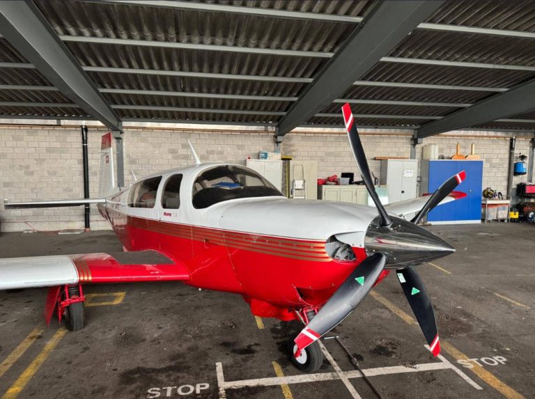 Red and white airplane parked in hangar