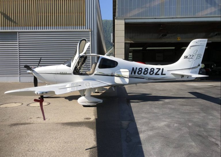 White airplane parked outside a hangar