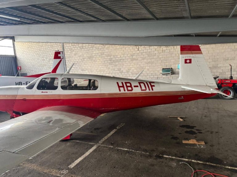 Red and white aircraft parked indoors.
