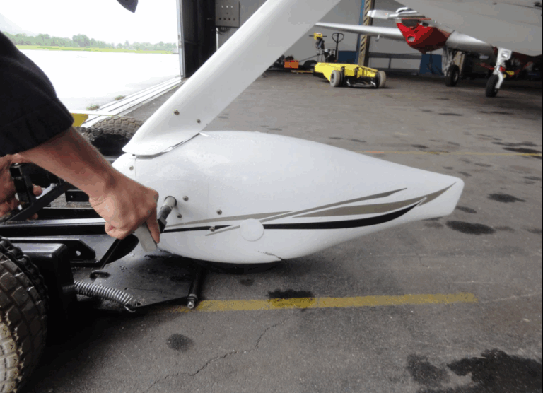 Person attaching propeller to small aircraft in hangar.