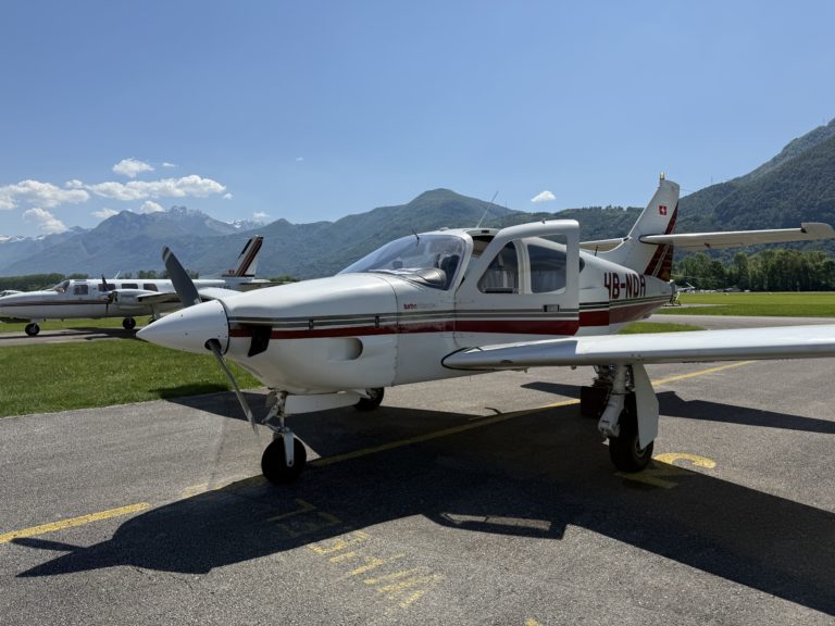 Small airplane on runway with mountains in background.