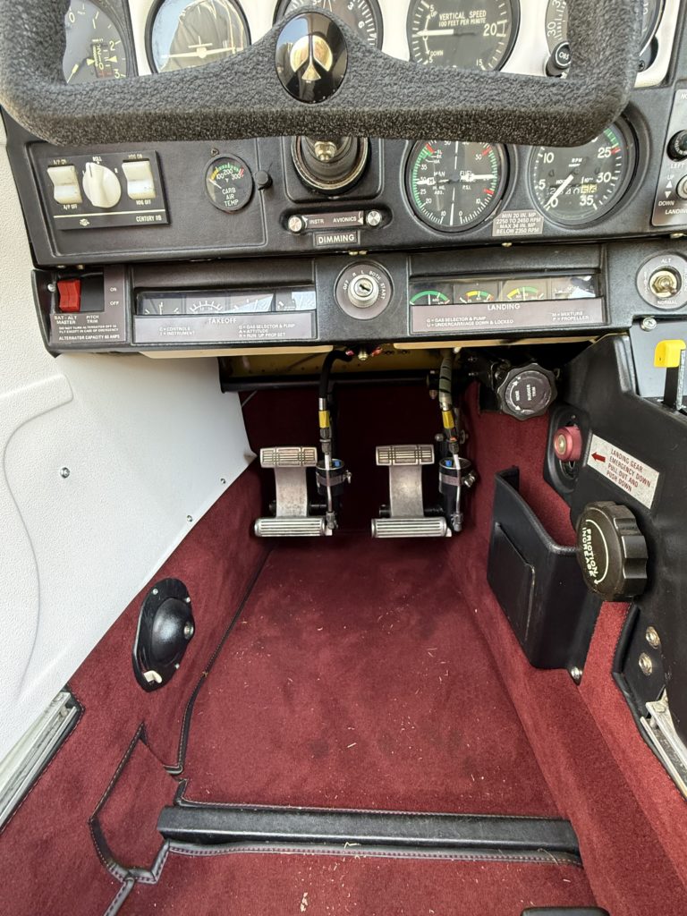 Small aircraft cockpit controls and foot pedals.