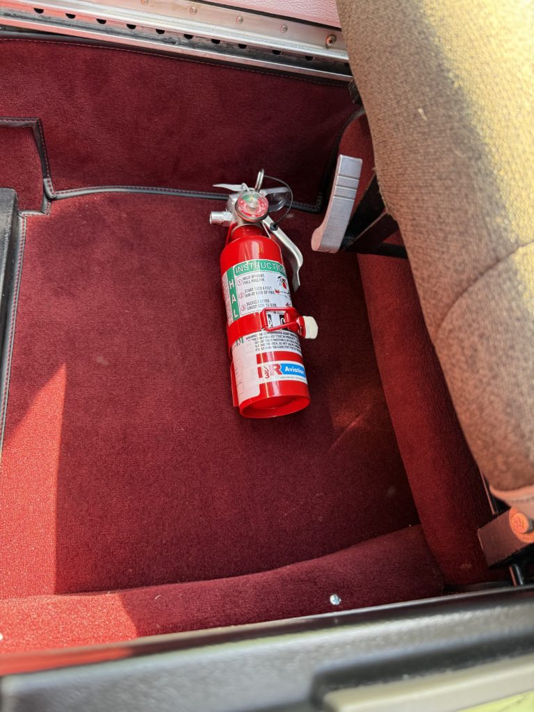 Red fire extinguisher on carpeted car floor