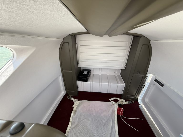 Airplane luggage compartment with red carpet and straps.