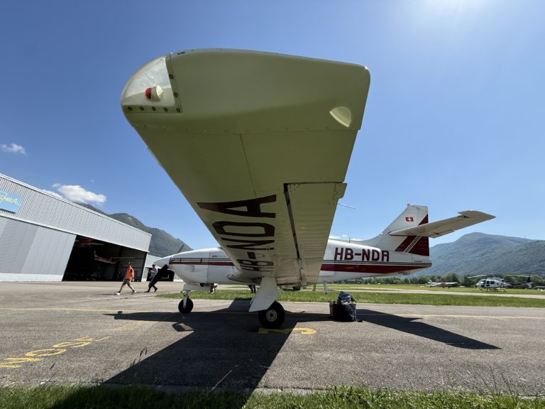 Small plane parked near hangar on sunny day.
