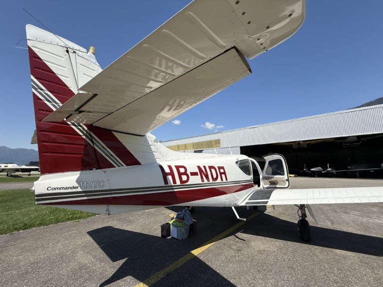 Red and white Commander 112TC airplane parked at airfield.