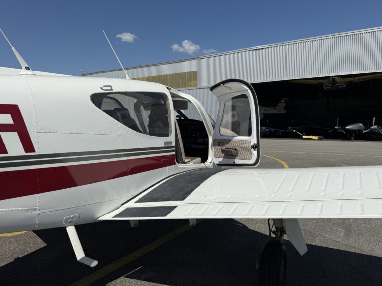 Small aircraft parked with an open cabin door.