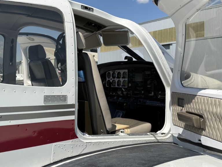 Small airplane cockpit with open door.