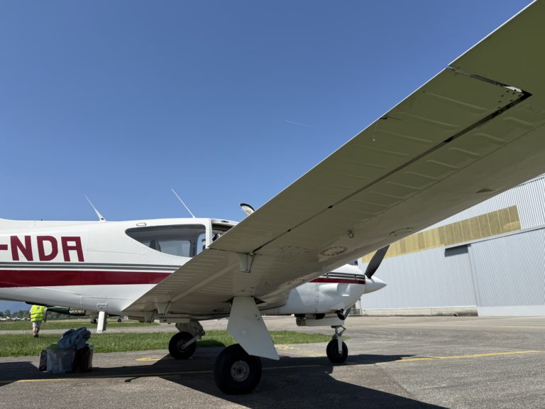 Small airplane parked on sunny tarmac.