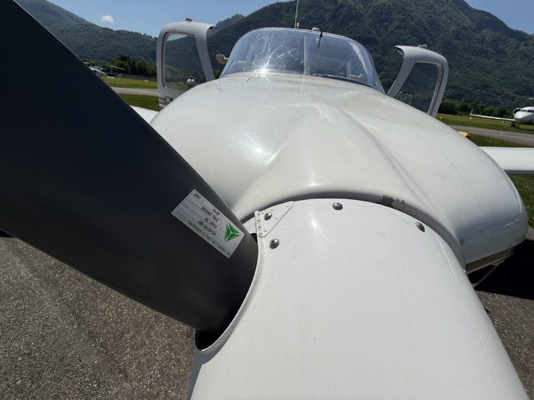 Close-up of airplane propeller and fuselage on runway.