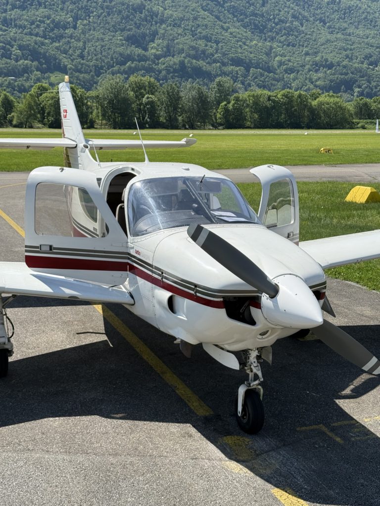 Small airplane parked on airfield with open door