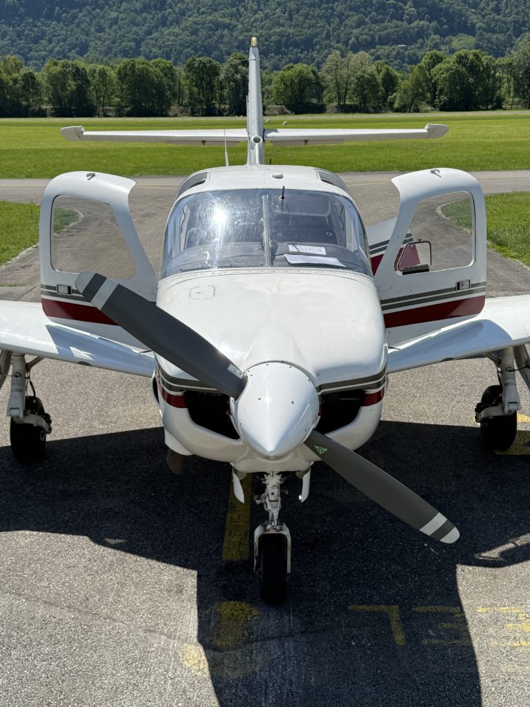 Small airplane parked on tarmac with open doors.