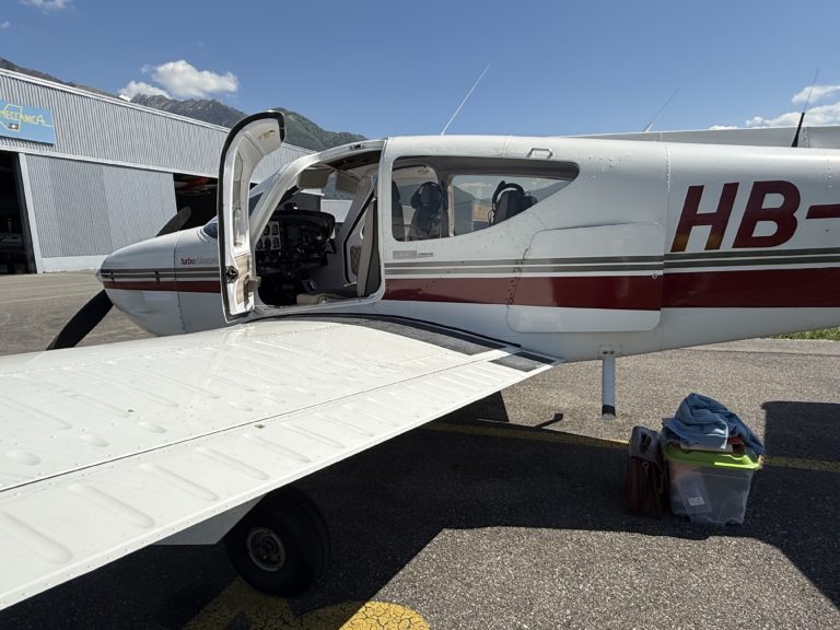 Small airplane parked on runway with open door.