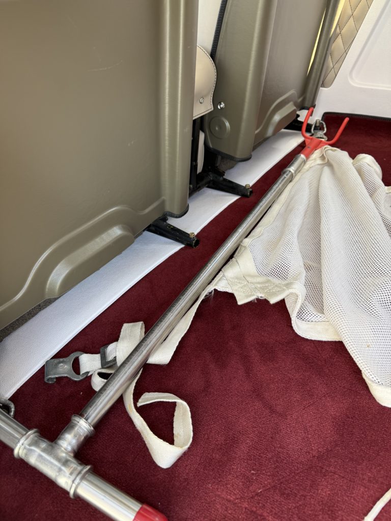 Airplane floor with red carpet and metal rods.
