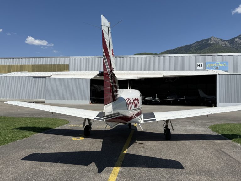 Airplane parked outside a hangar on a sunny day.