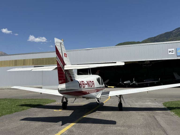 Small airplane parked in front of hangar.
