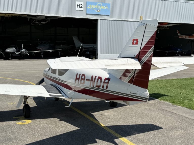 Small airplane parked outside hangar.