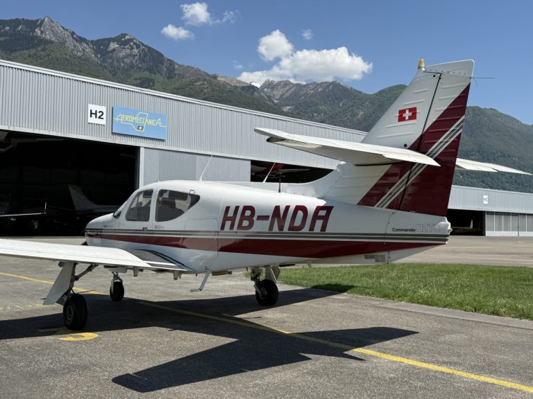 Small airplane parked at mountain hangar.