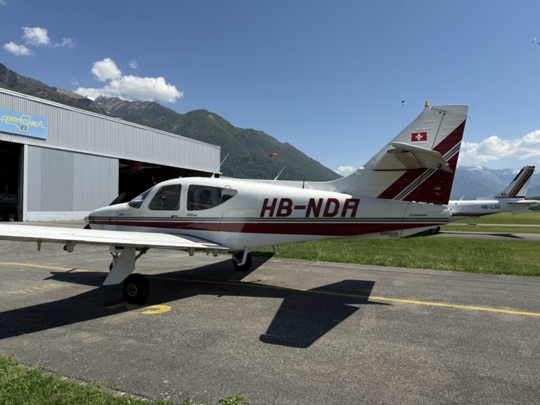 Small airplane parked outside hangar on clear day.