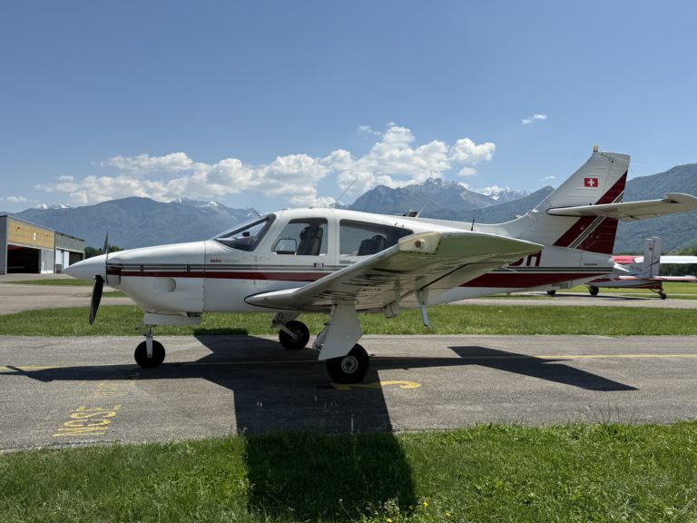 Small airplane on runway with mountain backdrop.