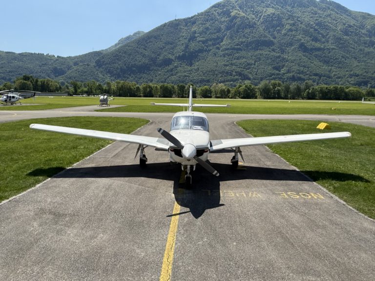 Small airplane parked on airstrip near mountains