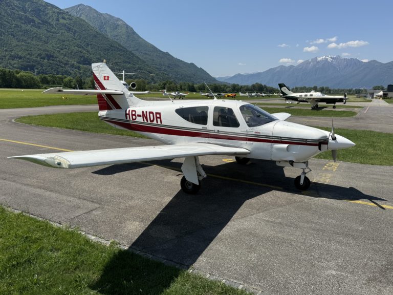 Small airplane on a runway with mountain backdrop.
