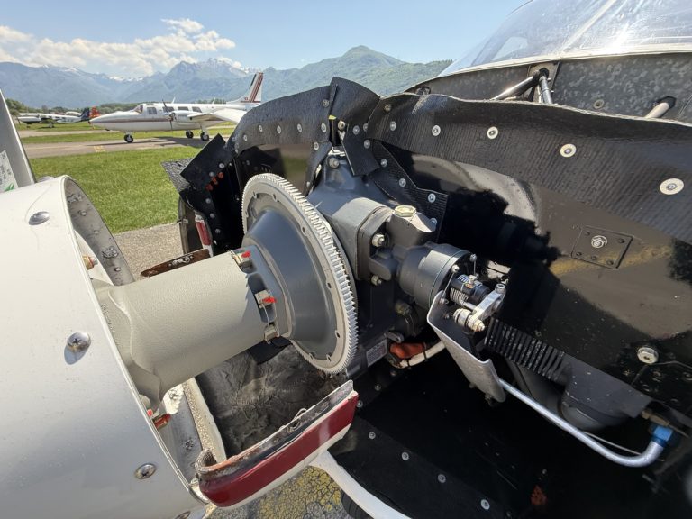 Close-up of airplane engine with mountains in background.